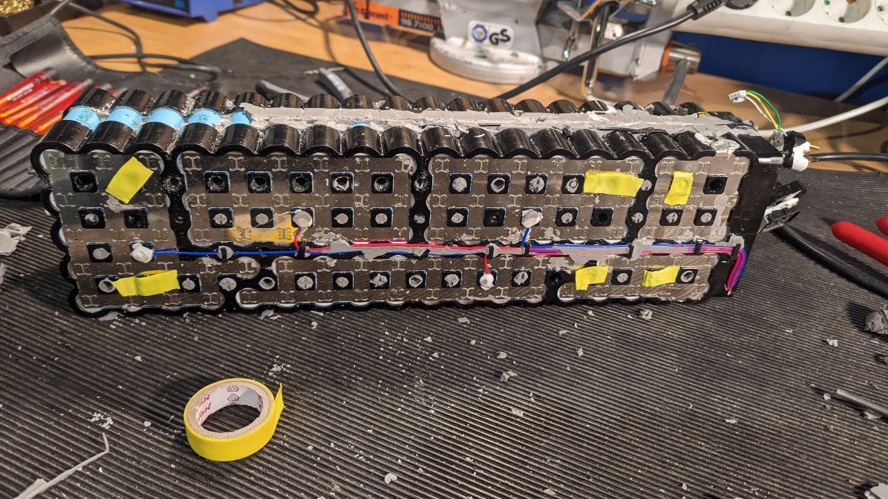 A battery pack with yellow electrical tape over some holes